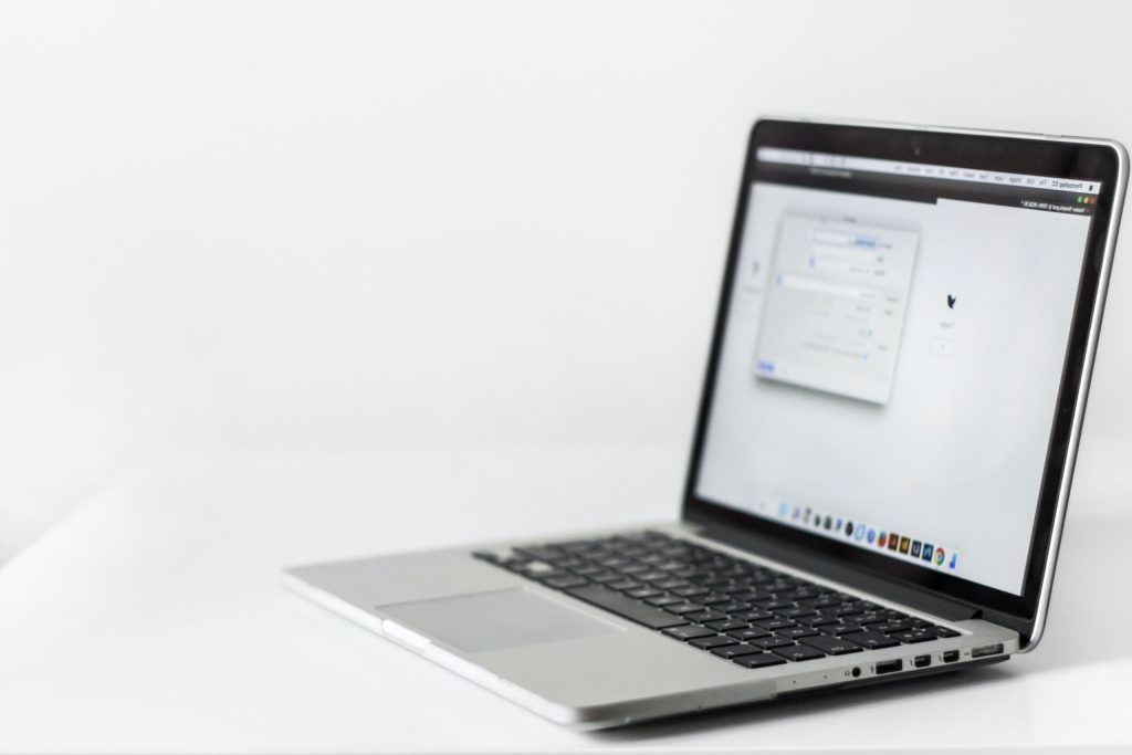 An open laptop on a plain white desk.