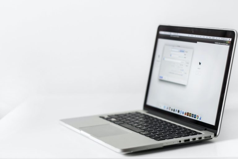 An open laptop on a plain white desk.