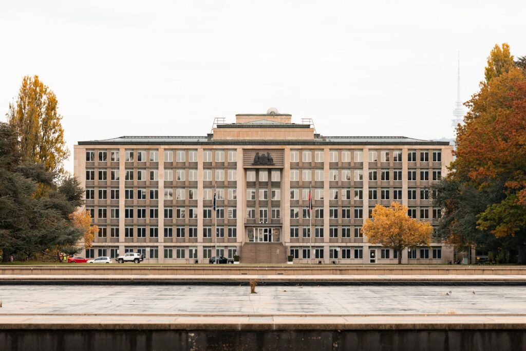 Historic government building in Canberra framed by autumn trees — Véurr Financial Planning specialist advice on Division 296 super tax, the $3M cap, CSS and PSS defined-benefit interaction, and Total Superannuation Balance planning