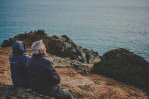 Older couple sitting on rocks looking out across the water at golden hour — symbolising retirement planning and long-term financial security in Australia.