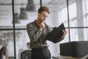 Public servant thoughtfully reviewing paperwork in a modern office while weighing a redundancy decision.