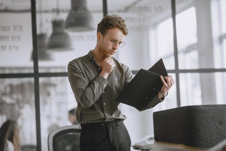 Public servant thoughtfully reviewing paperwork in a modern office while weighing a redundancy decision.