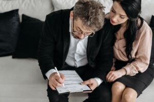 Couple working through claim paperwork together on a clipboard in a bright, neutral living room.