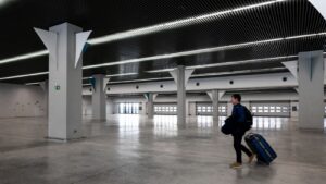 A lone traveller walking through an empty modern airport terminal with a suitcase, on the way to an overseas posting