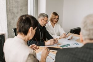 Advisers and clients reviewing financial charts and documents together at a table in a bright office.