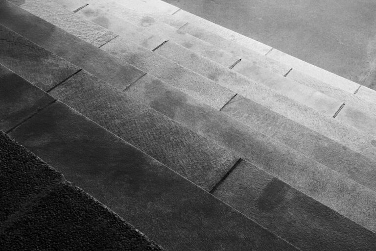 Black and white photo of wide stone steps rising diagonally to a flat paved landing.